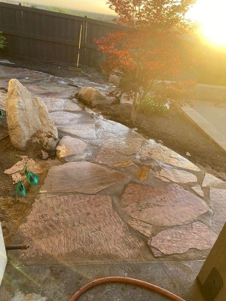 Natural stone pathway with a sunset, surrounded by landscaping and decorative rocks.