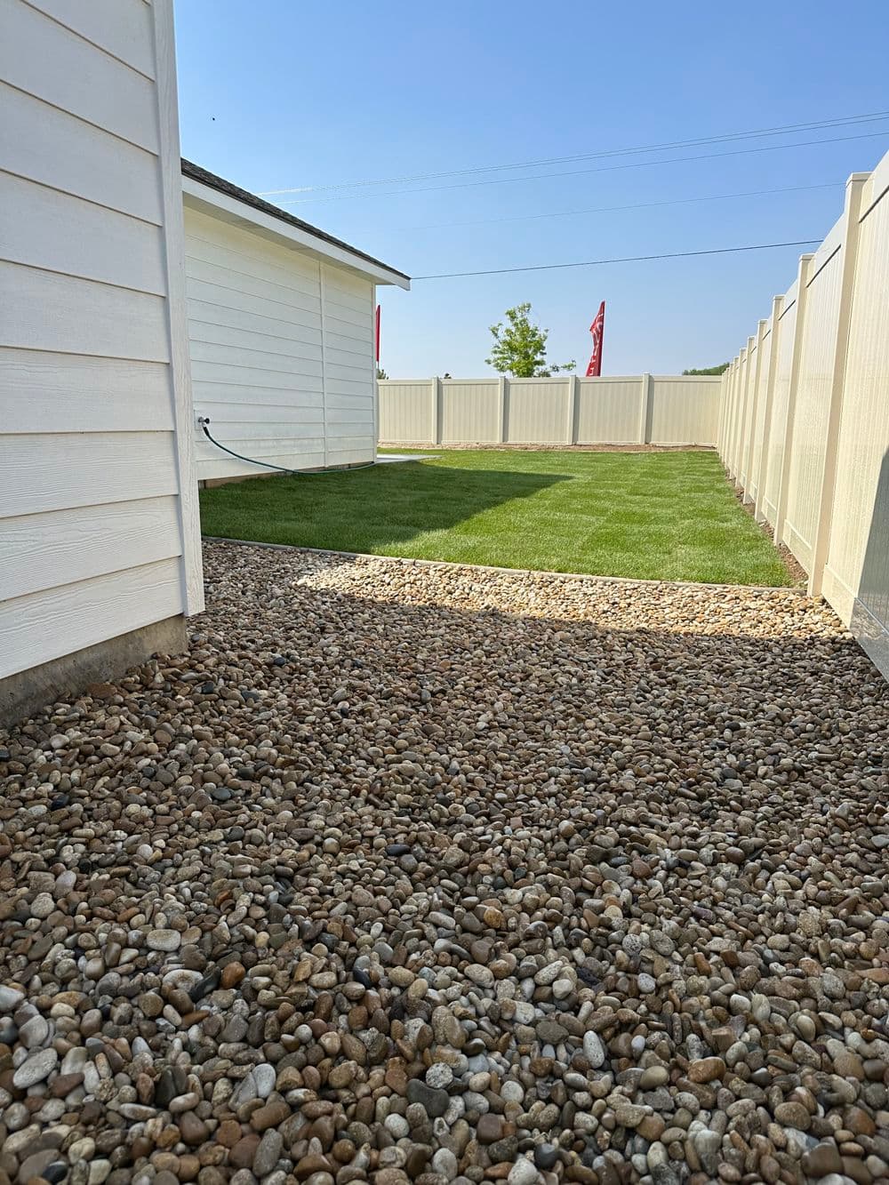 Gravel pathway leading to a well-manicured lawn in a fenced backyard.